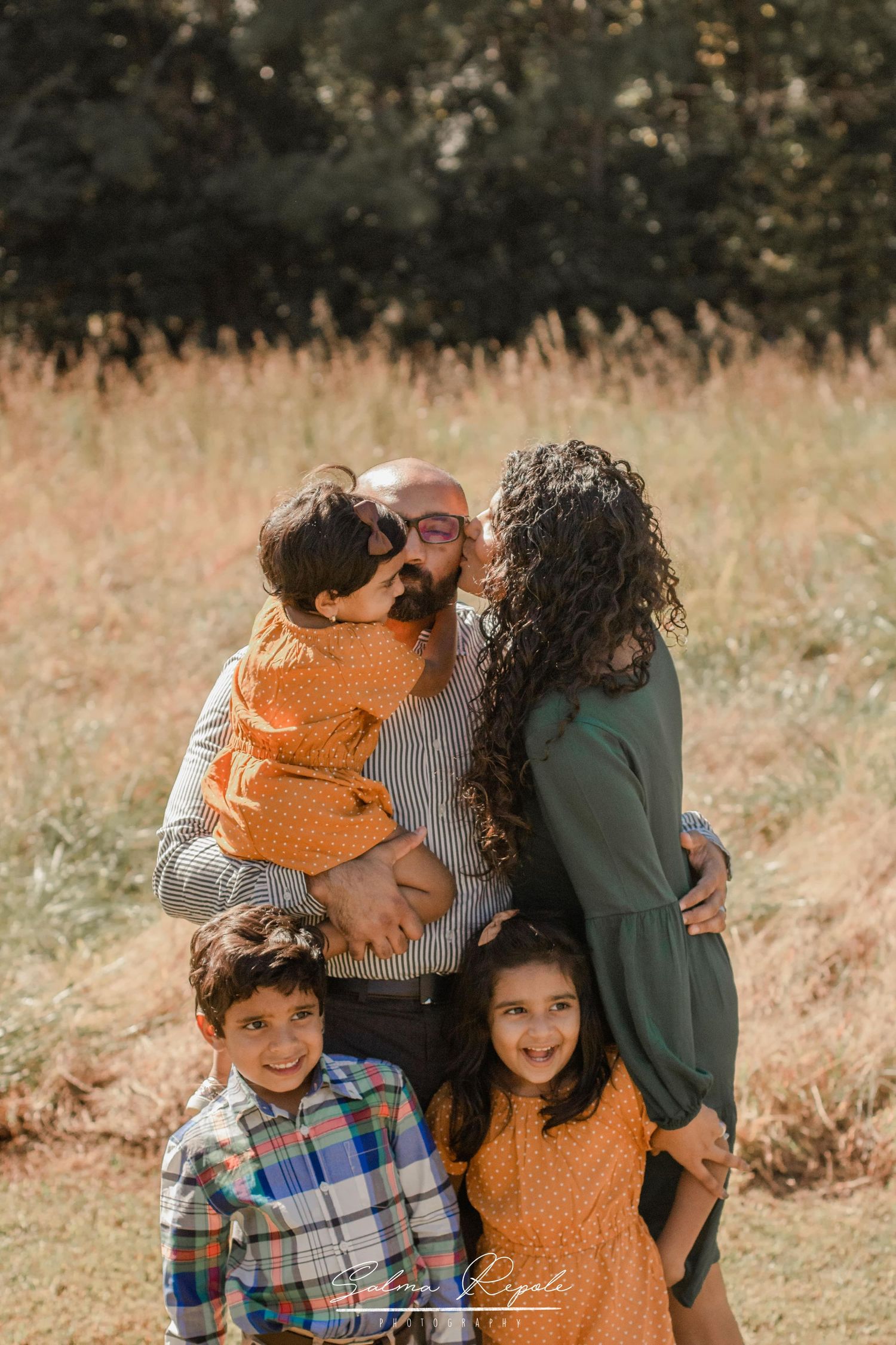 Family group poses together in casual autumn outfits during outdoor photo session.