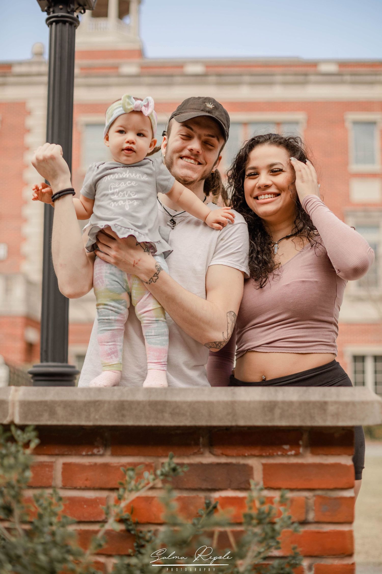 Family enjoying a casual moment together on a brick ledge during an outdoor photoshoot.
