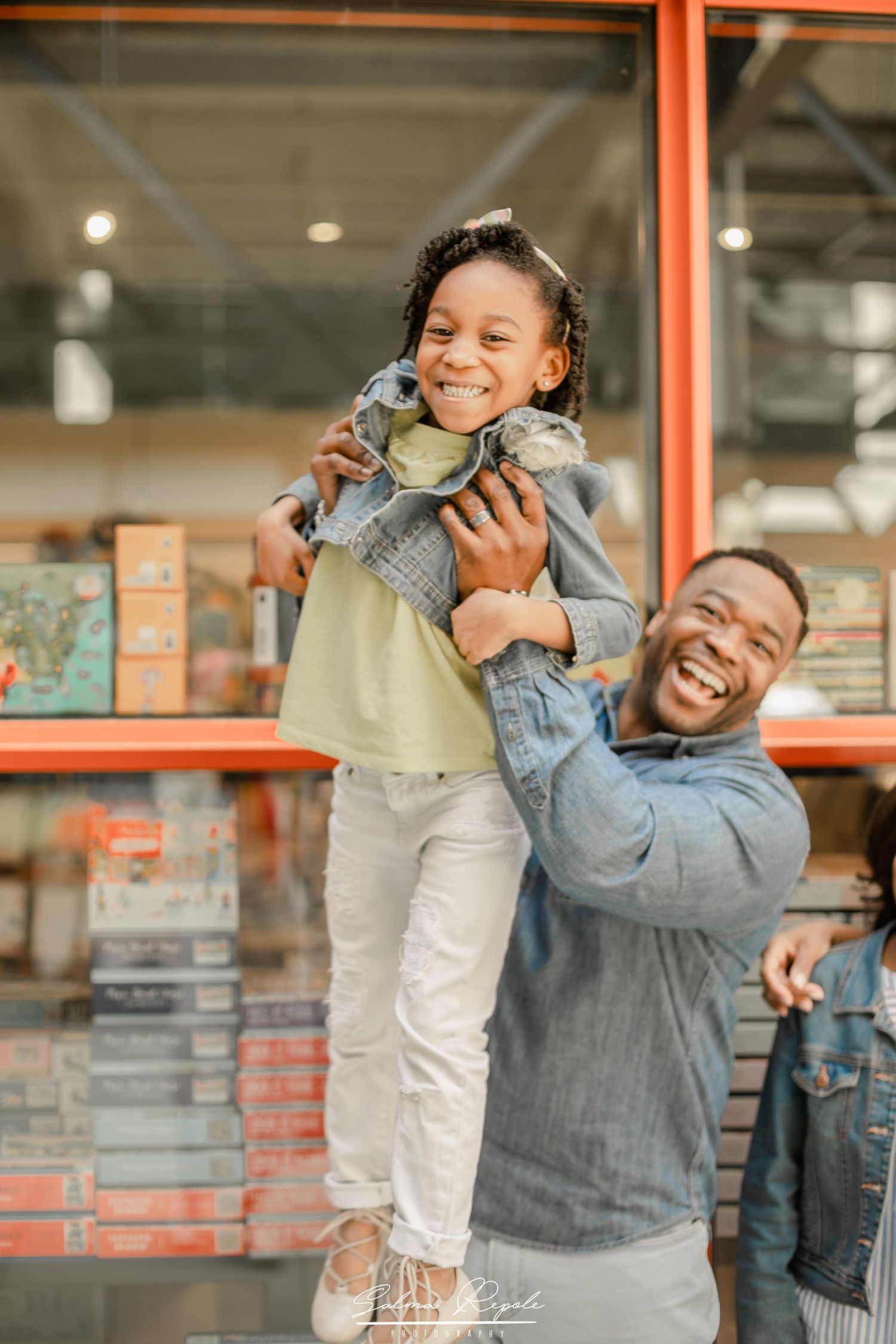 Candid moments of a family laughing and playing together outside a modern building.