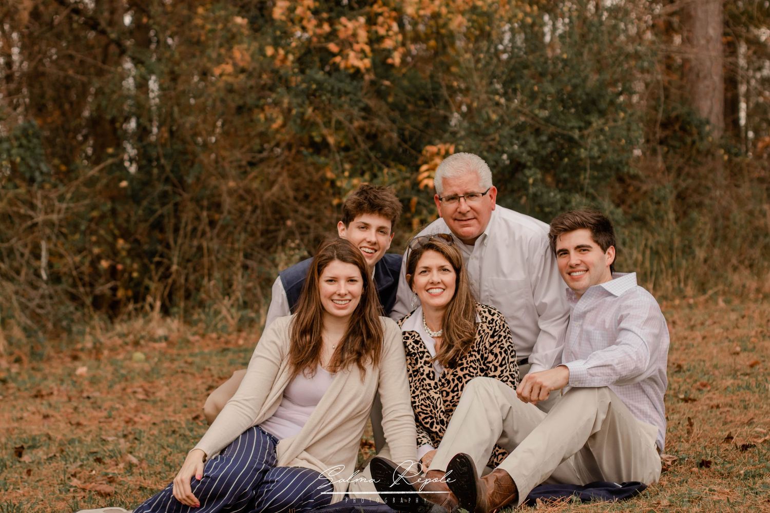 Family members pose together in warm autumn light against a natural outdoor backdrop.