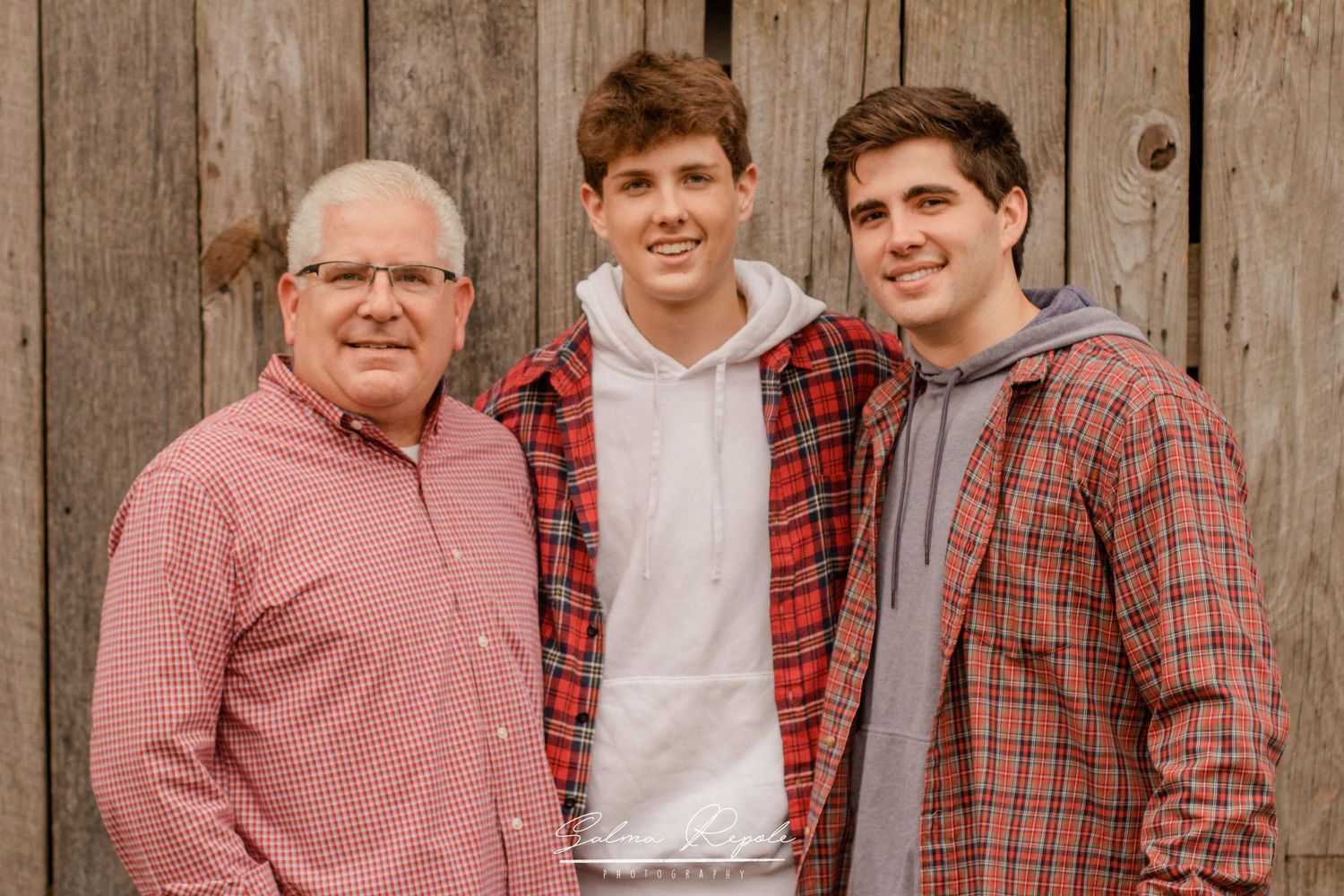 Group portrait against rustic wooden fence wearing coordinated red and white outfits.