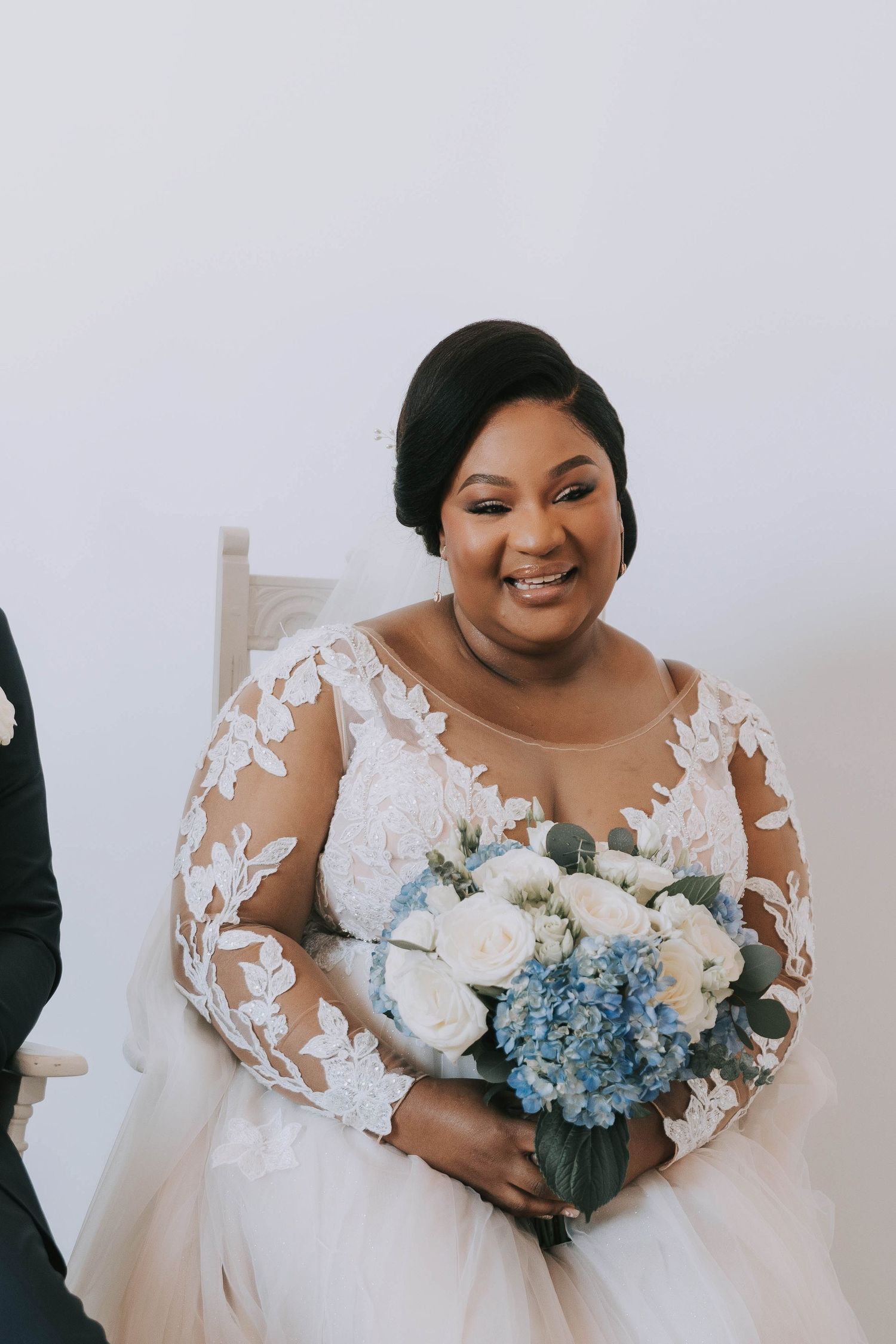 Beautiful bride in lace gown holding blue and white bouquet.