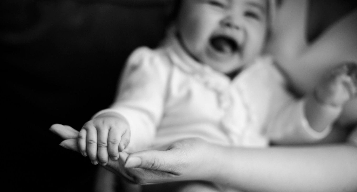 black and white photo of a happy baby holding her mother's hand.