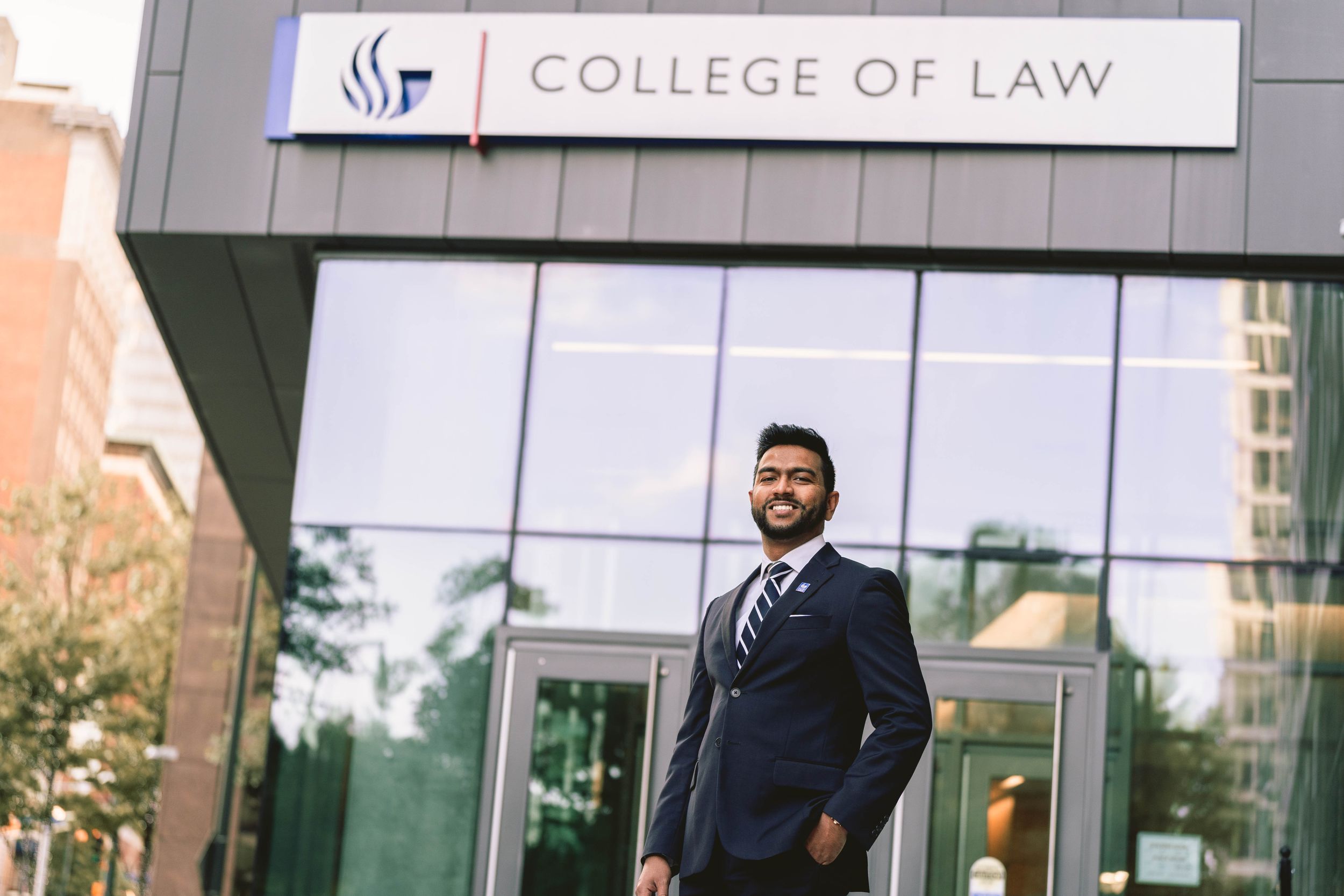 Professional portrait outside a modern College of Law building entrance.