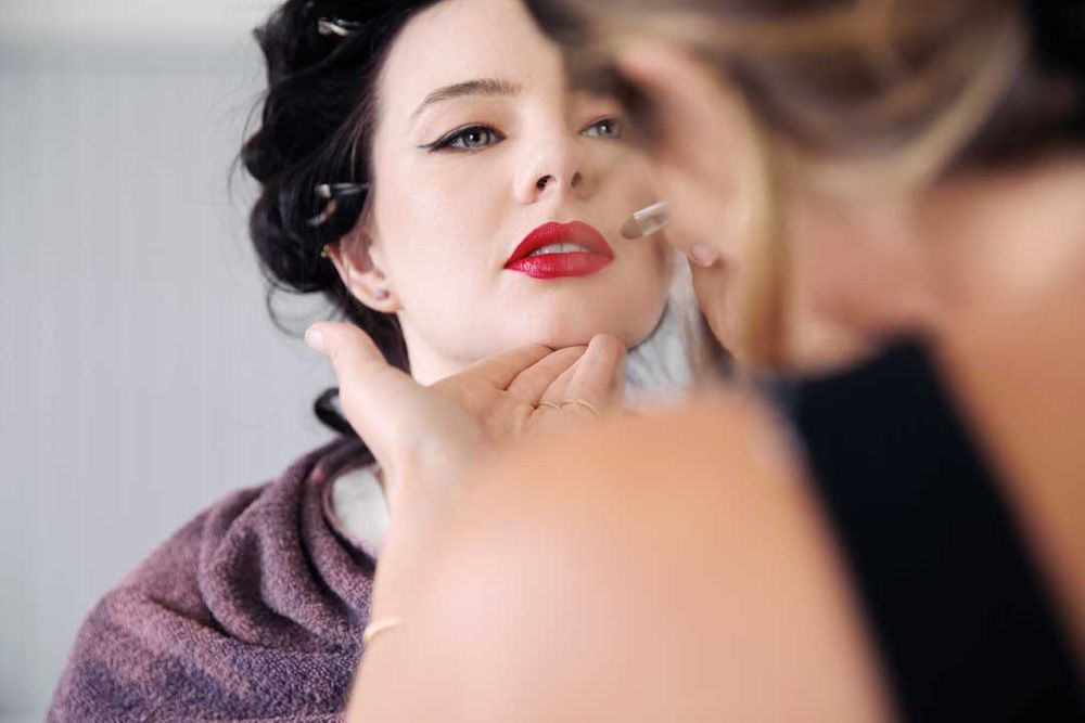 A close-up beauty shot showing red lipstick and dark curled hair.