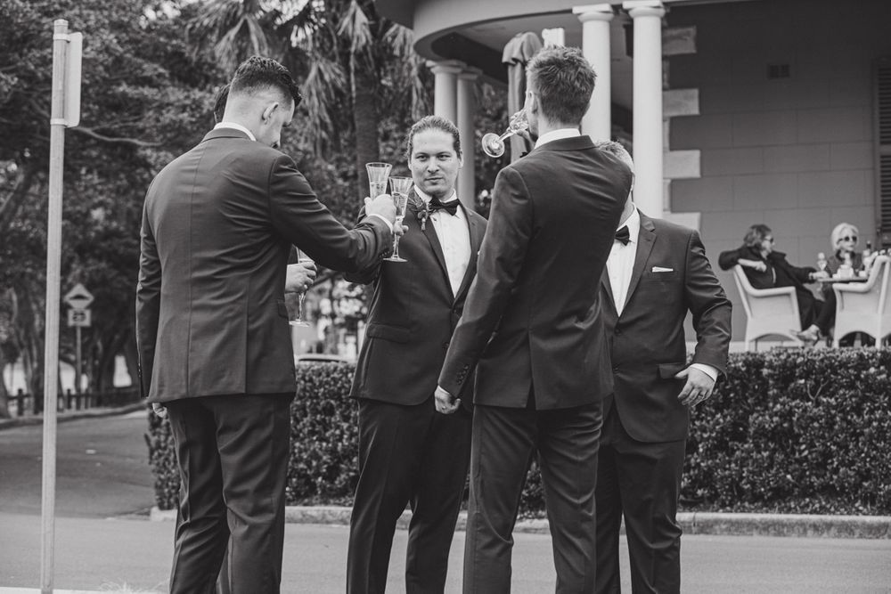 Groomsmen in dark suits stand together during outdoor wedding celebration.