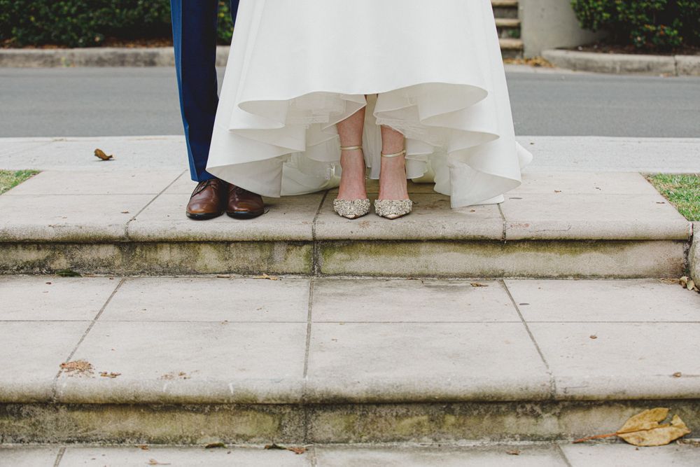 Close-up view of wedding party members' feet standing on stone pathway.