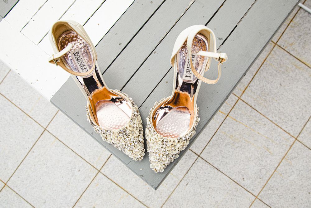Sparkly bridal shoes positioned in a V shape on white wooden flooring.