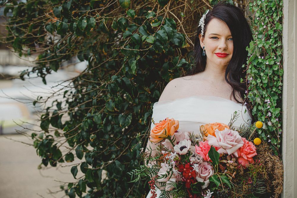Bridal portraits with colorful floral bouquet against an ivy-covered wall.