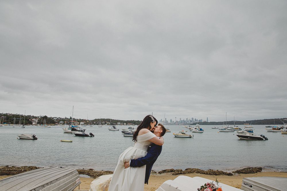 Waterfront wedding photo with boats and harbor in the background.