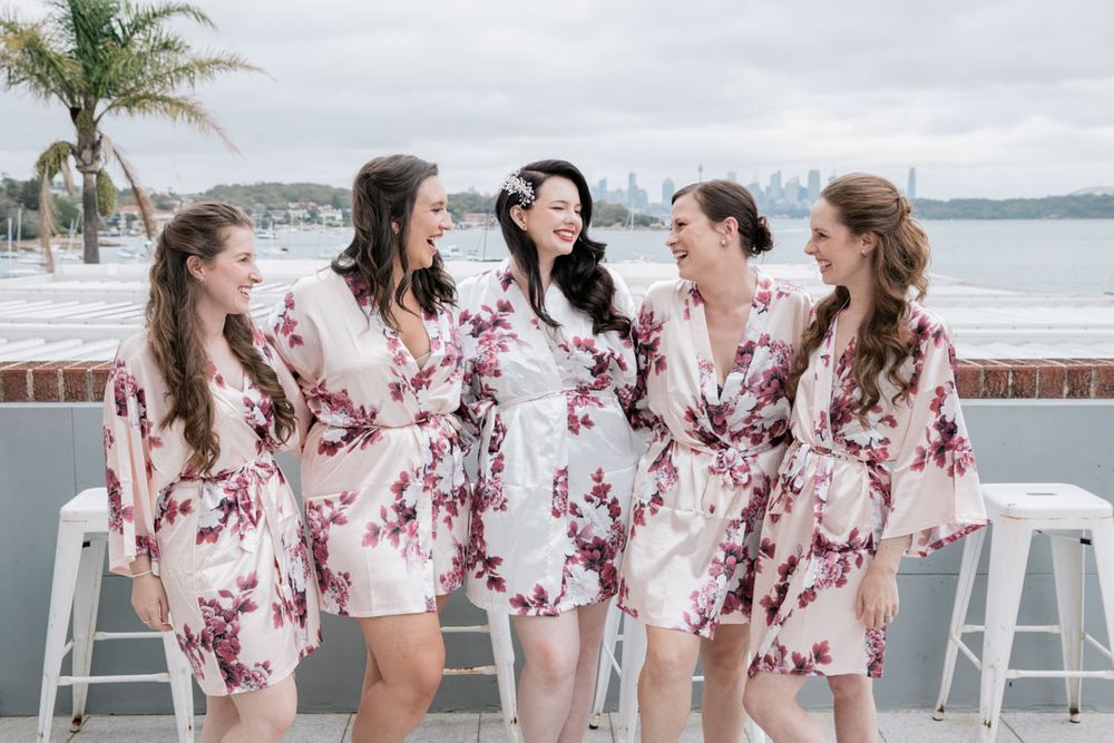 A group wearing matching floral robes laughs together by the waterfront.