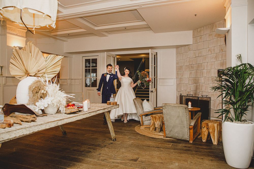 Modern coastal venue interior with white walls, wooden floors and decorative palm fronds.