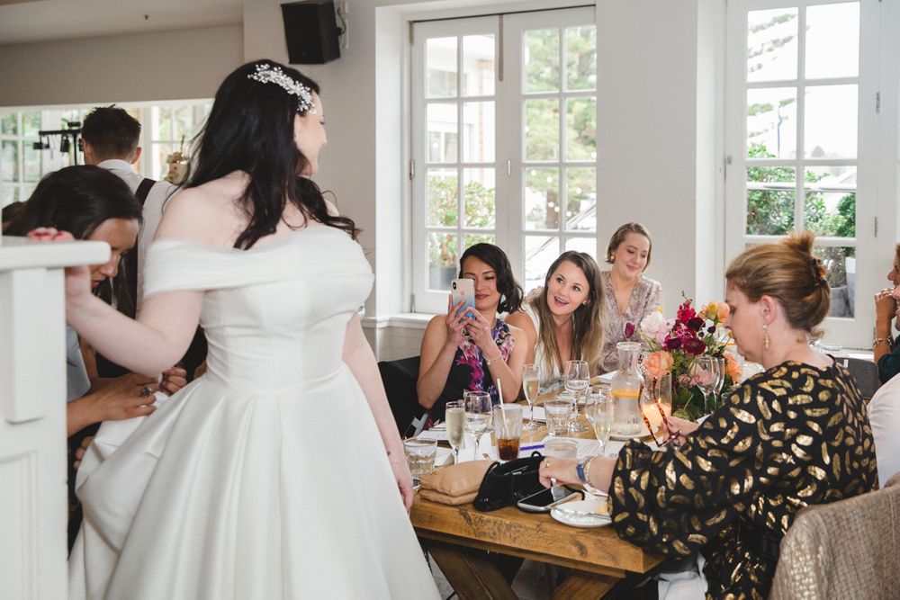 Wedding celebration in a bright white room with large windows and elegant table settings.