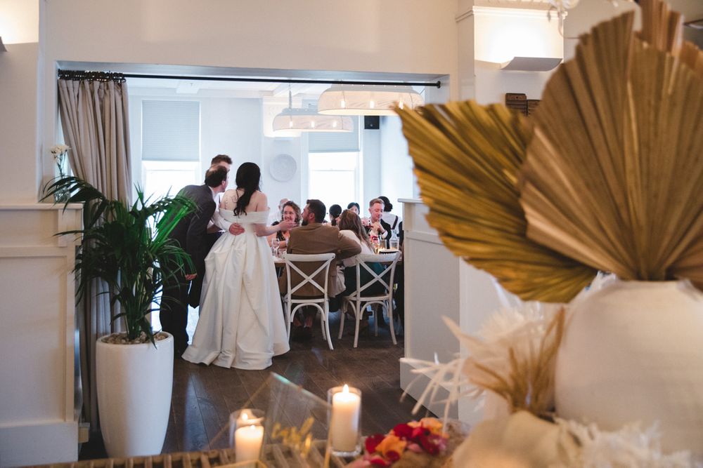 Wedding reception space with minimalist decor featuring dried palm leaves and white furnishings.