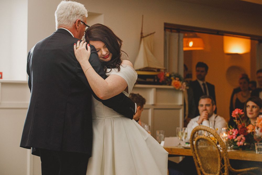 An emotional dance between two people in formal attire at an indoor reception.