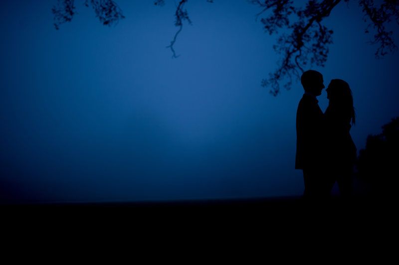 Silhouetted figures stand together against deep blue twilight sky.