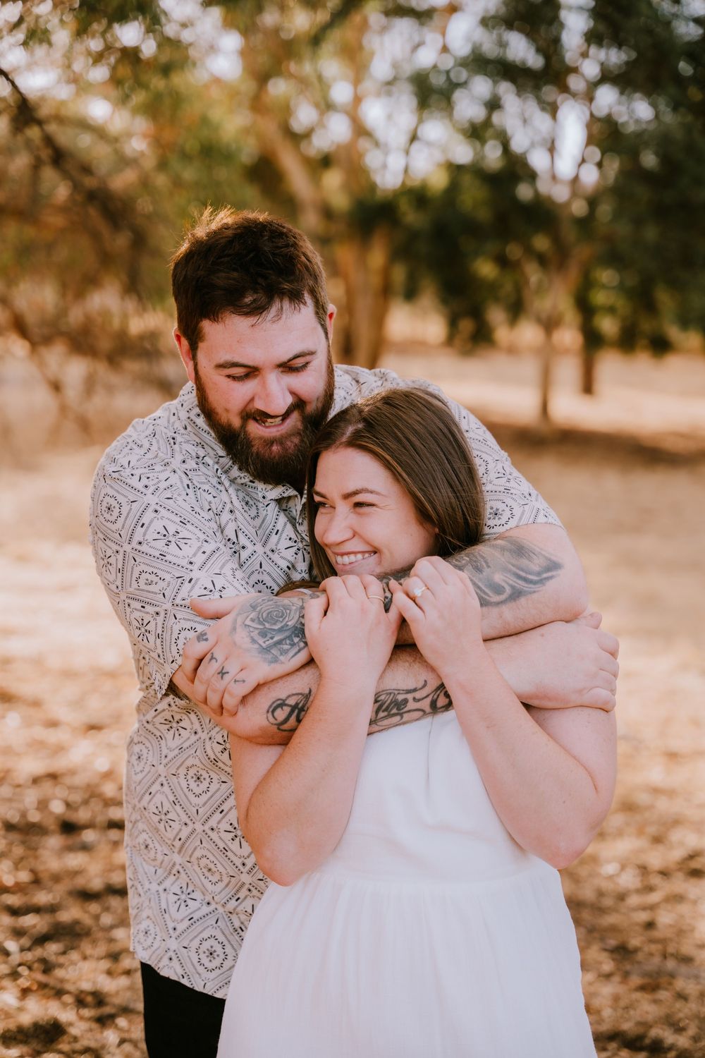 A couple embraces and laughs together during an outdoor photo session.