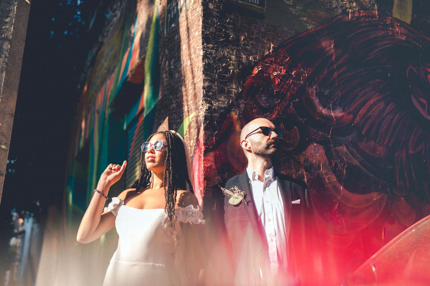 Stylish wedding couple posing against colorful urban graffiti wall.