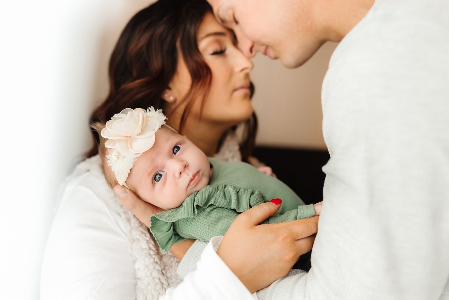 Intimate family portrait series showing tender moments between parents and baby.