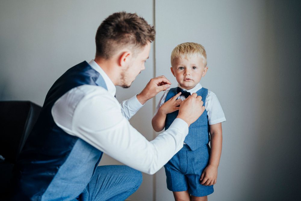 A touching moment between two people adjusting formal attire before an event.