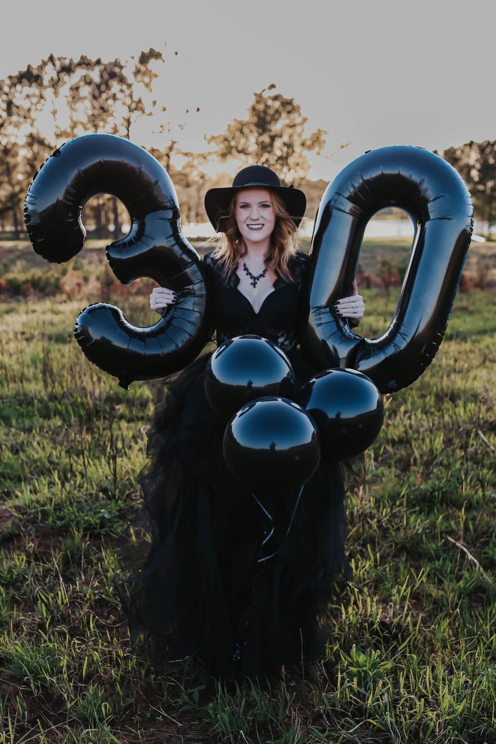Blue balloon numbers arranged on grassy field at sunset.