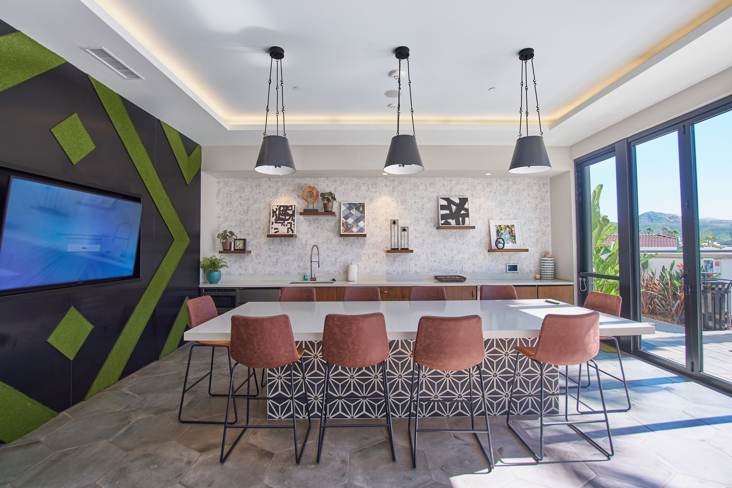 Modern conference room with geometric wall art, pendant lights, and coral-colored bar stools.