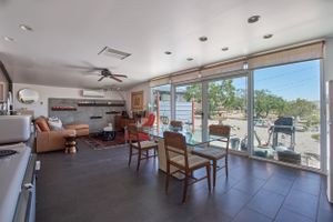 Modern dining area with large windows overlooking outdoor patio and panoramic views.