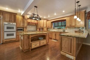 Luxurious rustic kitchen with natural wood cabinets, granite countertops, and modern stainless steel appliances.