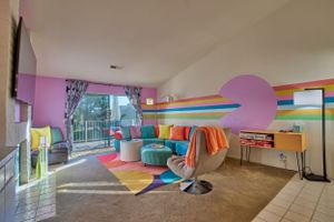 Colorful playroom with rainbow stripes, geometric decor, and comfy seating perfect for kids' entertainment.