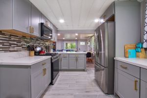 Modern grey kitchen with stainless appliances, white countertops and stylish hardware.