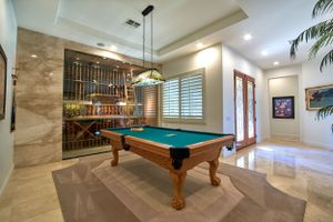 Elegant game room featuring pool table, custom wine storage, and modern lighting fixtures.