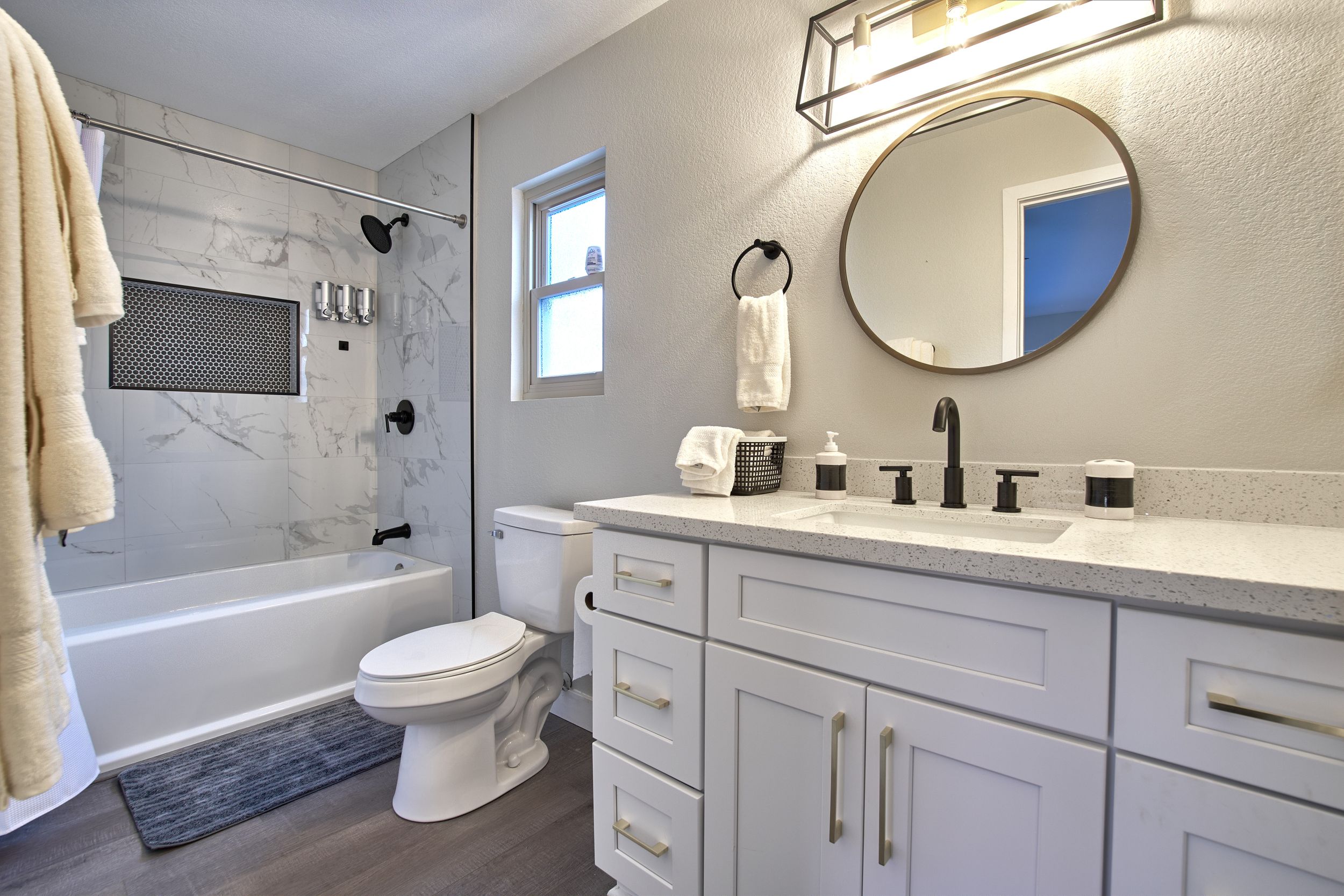 Modern white bathroom featuring marble tile, double vanity, and contemporary lighting fixtures.