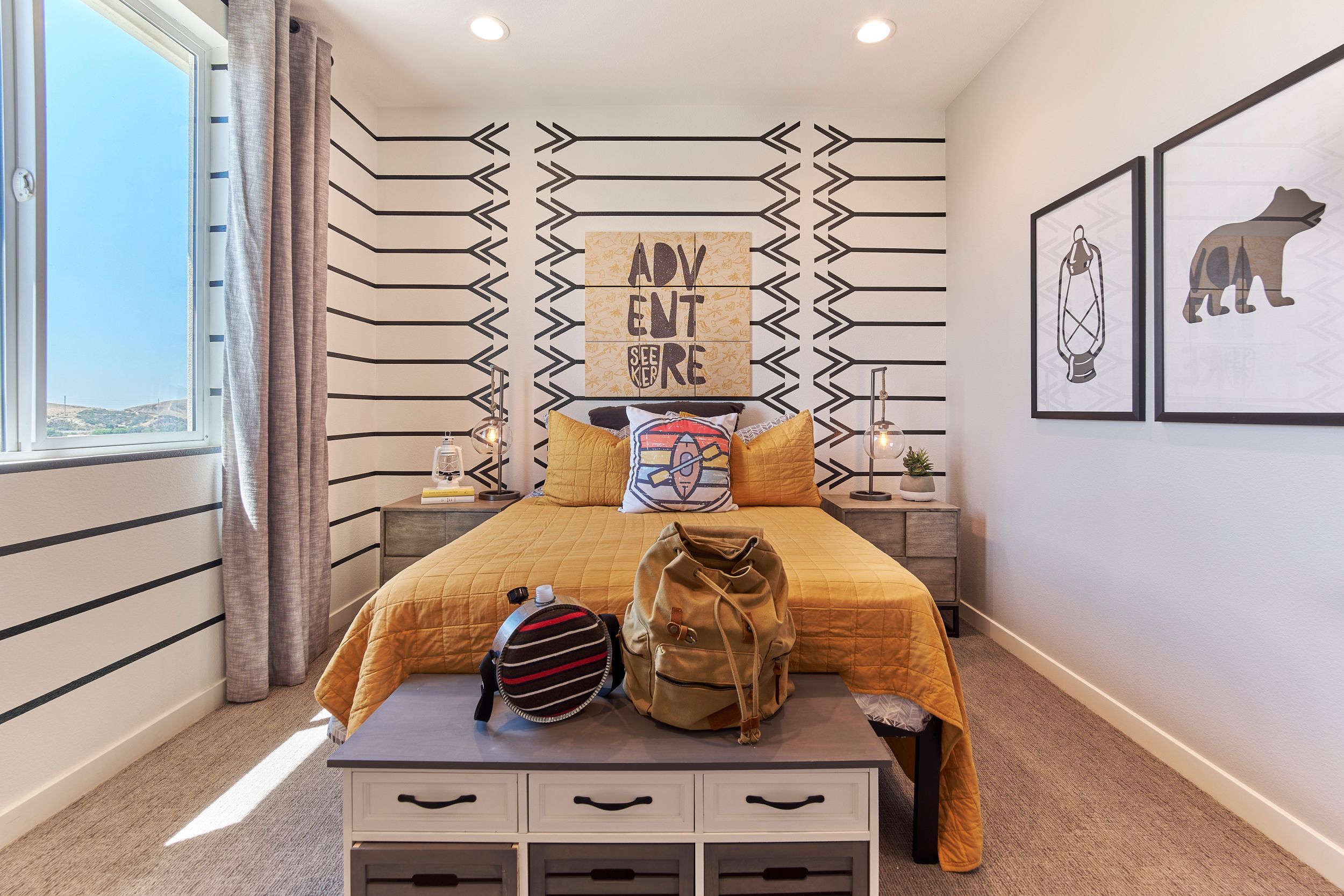 Modern bedroom with geometric arrow wall design, yellow bedding, and minimalist bear artwork.