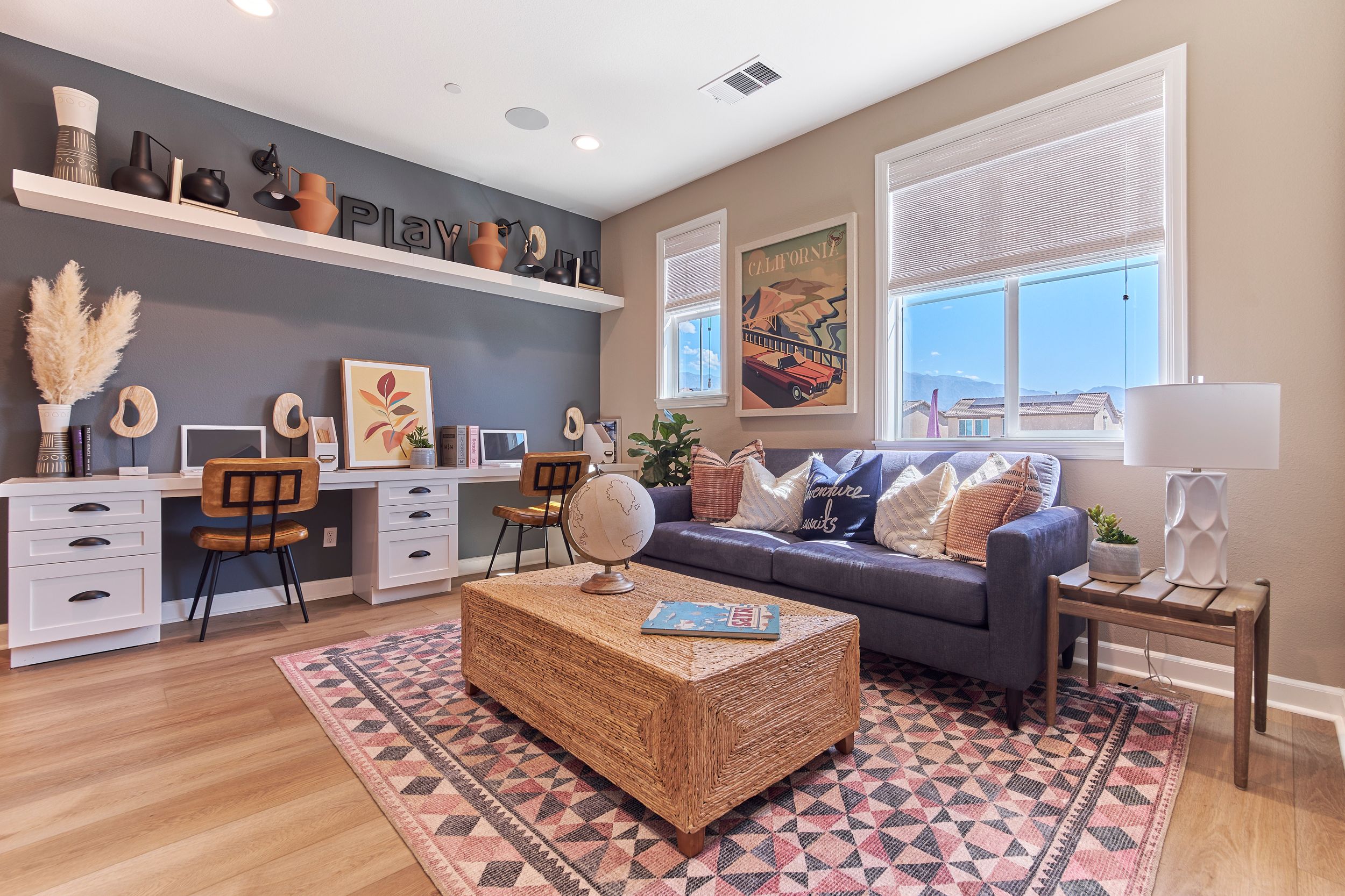 Contemporary home office and living room combo with navy accent wall and built-in desk space.