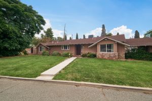 Single-story ranch home with brick exterior and well-maintained front lawn on a residential street.