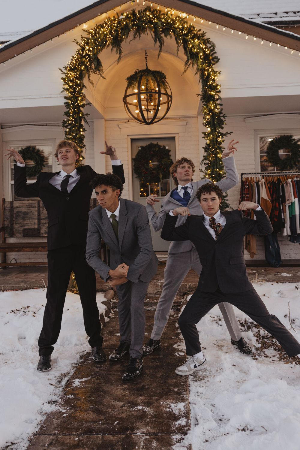 Wedding party strikes playful poses in front of an illuminated holiday entrance.