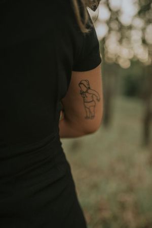Close-up of simple line drawing tattoo on person's arm.
