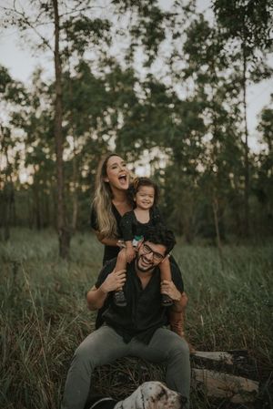 A joyful family playing and laughing together in a natural outdoor setting at sunset.