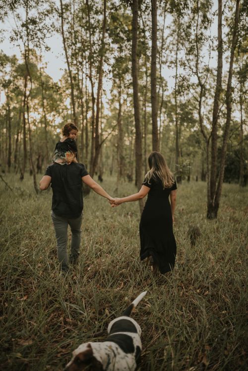 Couple walking through eucalyptus forest with dog following behind.