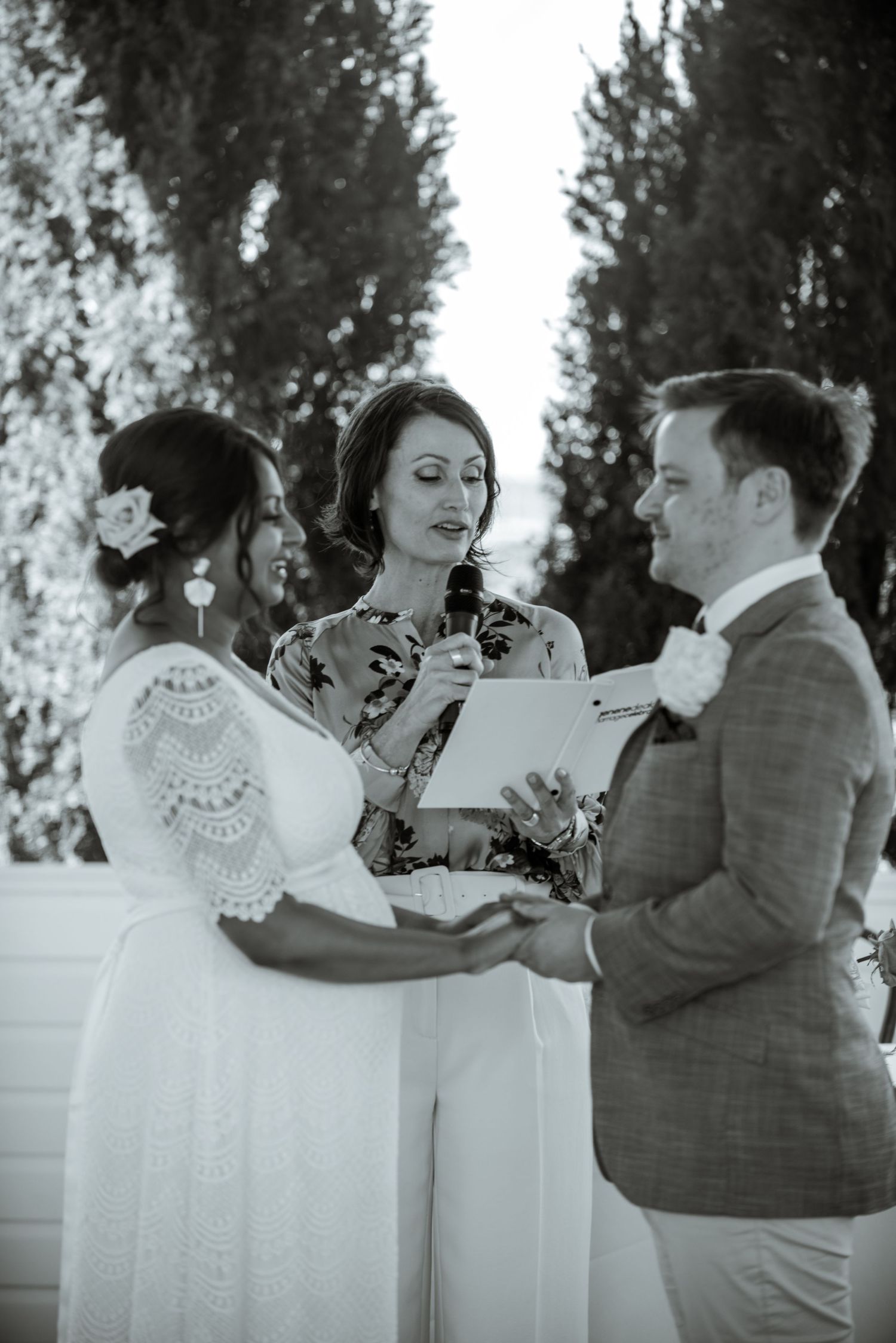 An intimate outdoor wedding ceremony with an officiant conducting the service in a garden setting.