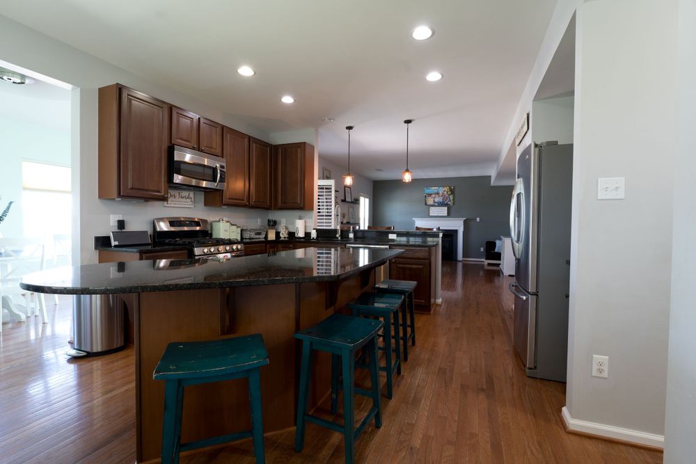 Modern kitchen with dark wood cabinets, granite countertops, and blue bar stools along an extended island.