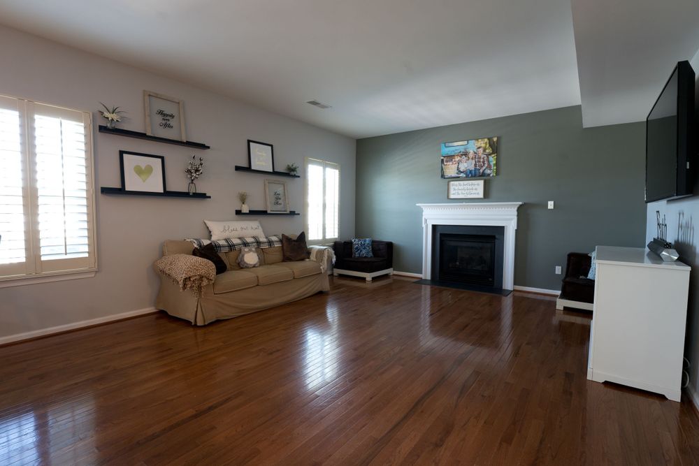 Living room with hardwood floors, accent wall, fireplace, and floating shelves displaying artwork.