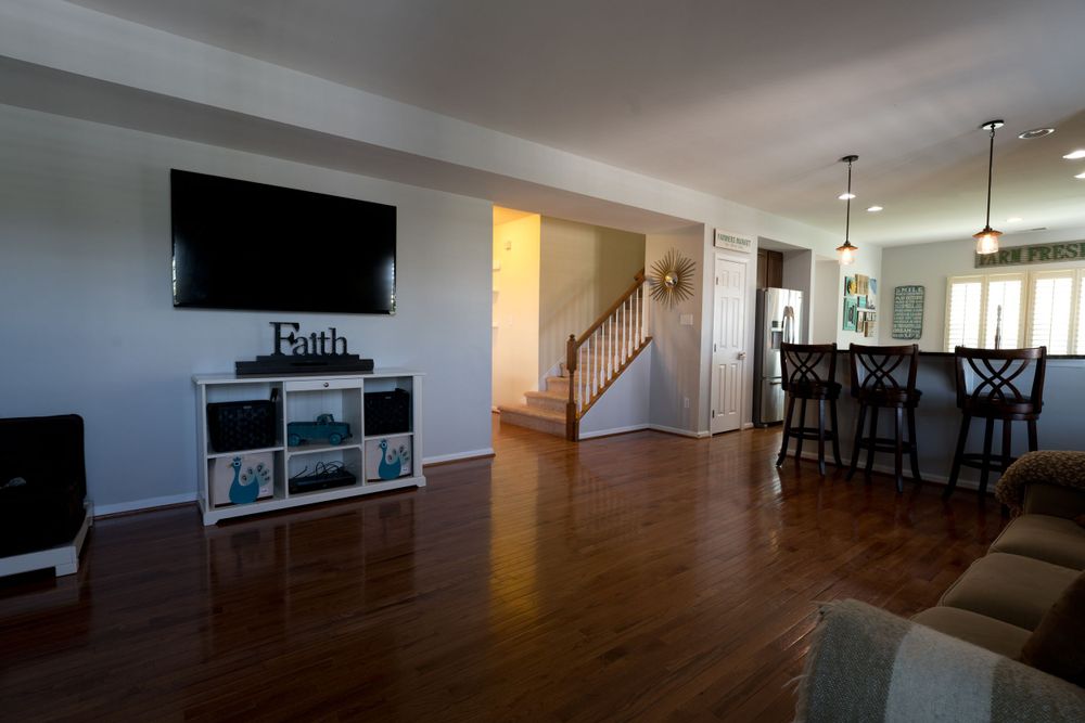 Open concept living area with mounted TV, entertainment center, and staircase leading upstairs.