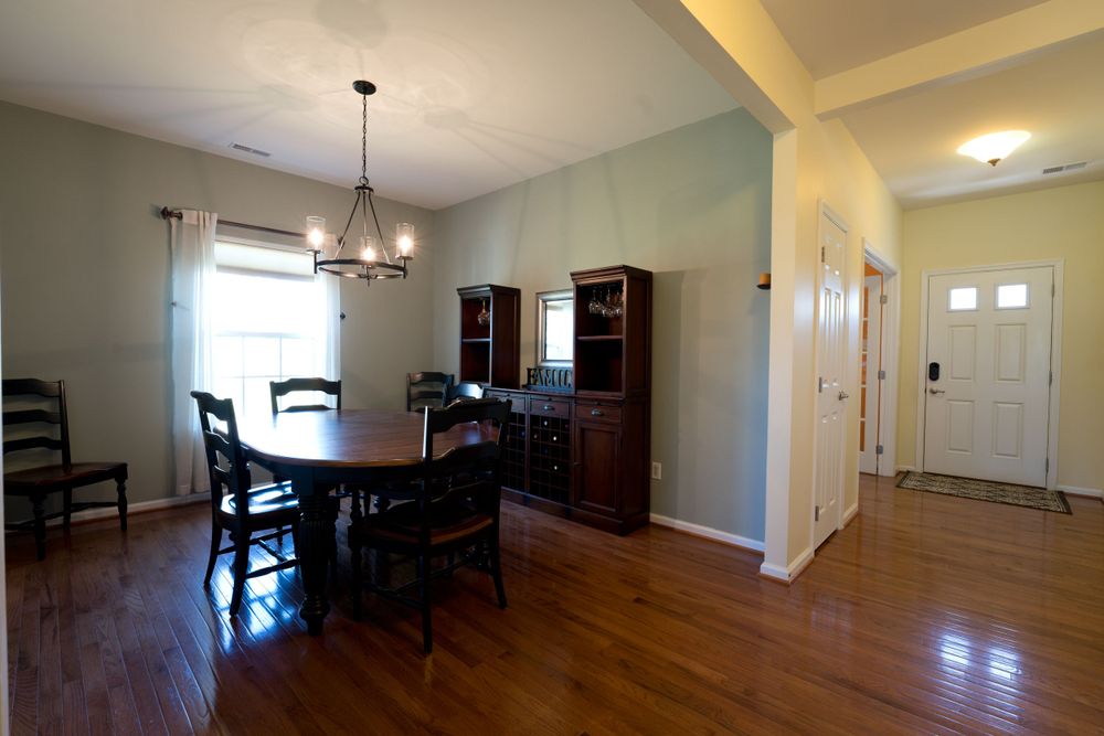 Dining area with dark wood furniture, chandelier, and white trim against mint green walls.