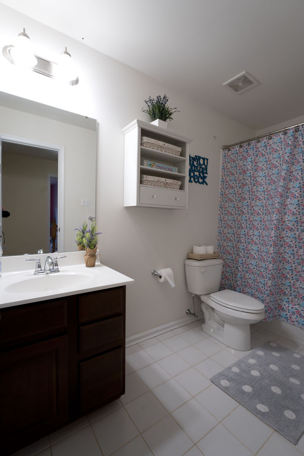 Contemporary bathroom with dark wood vanity, white fixtures, and patterned shower curtain.
