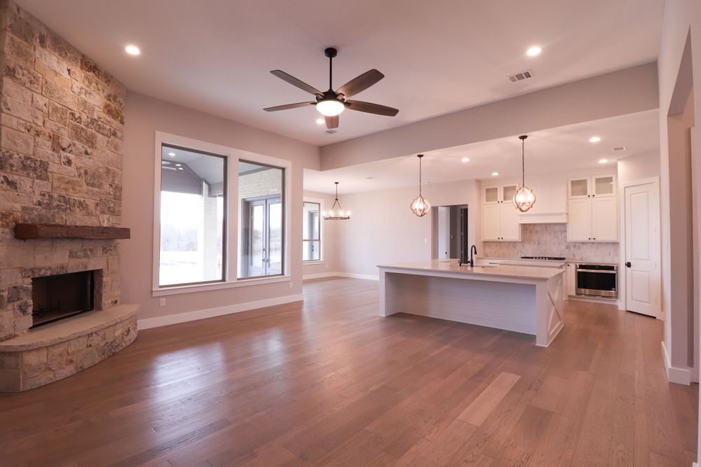 Open concept living room and kitchen with stone fireplace, hardwood floors, and large kitchen island.