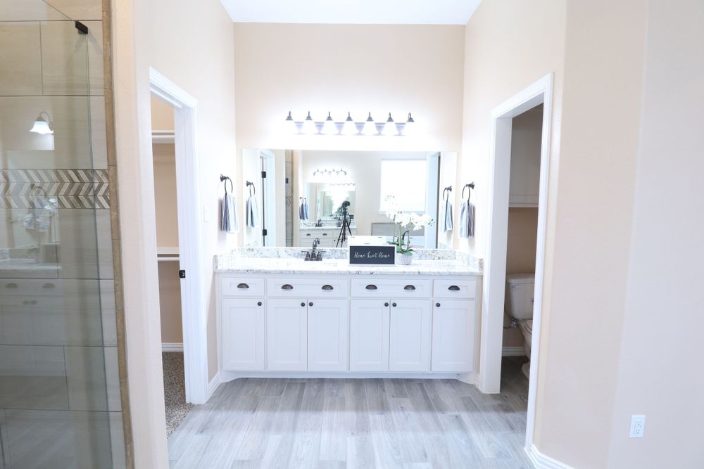 Elegant master bathroom with white double vanity, large mirror, and wood-look tile flooring.