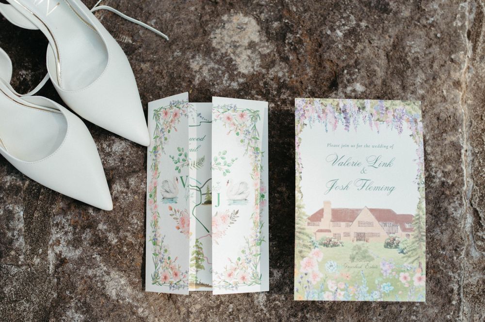 White bridal shoes next to floral wedding invitations with soft watercolor designs.