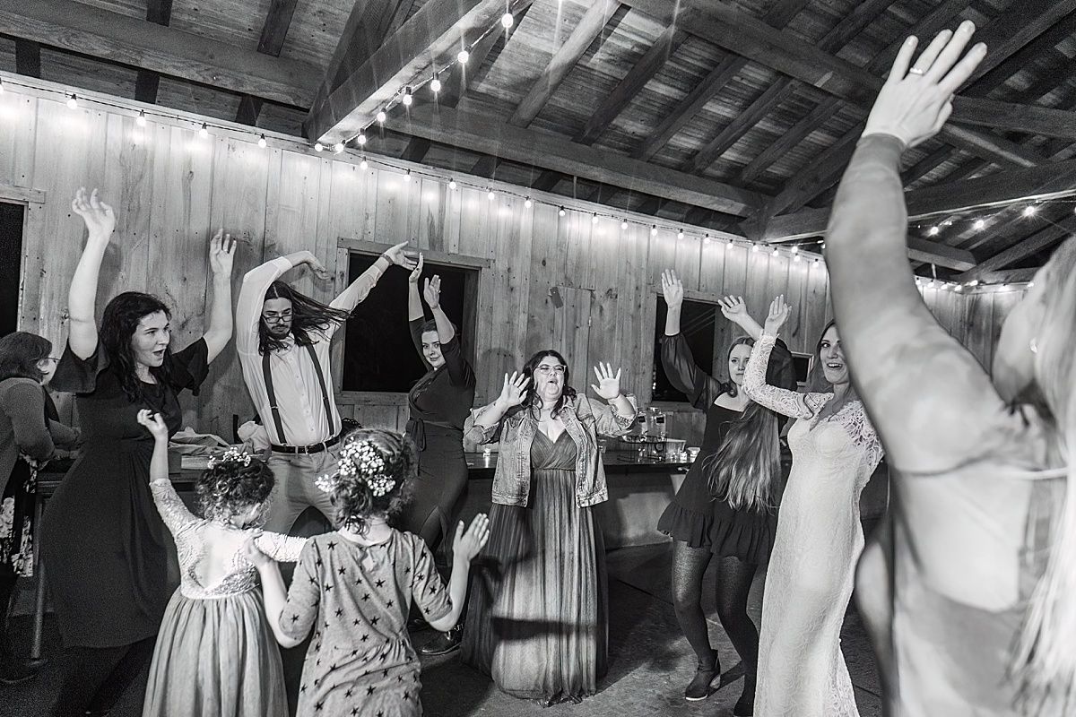 Photography of wedding guests dancing with arms up at wedding reception