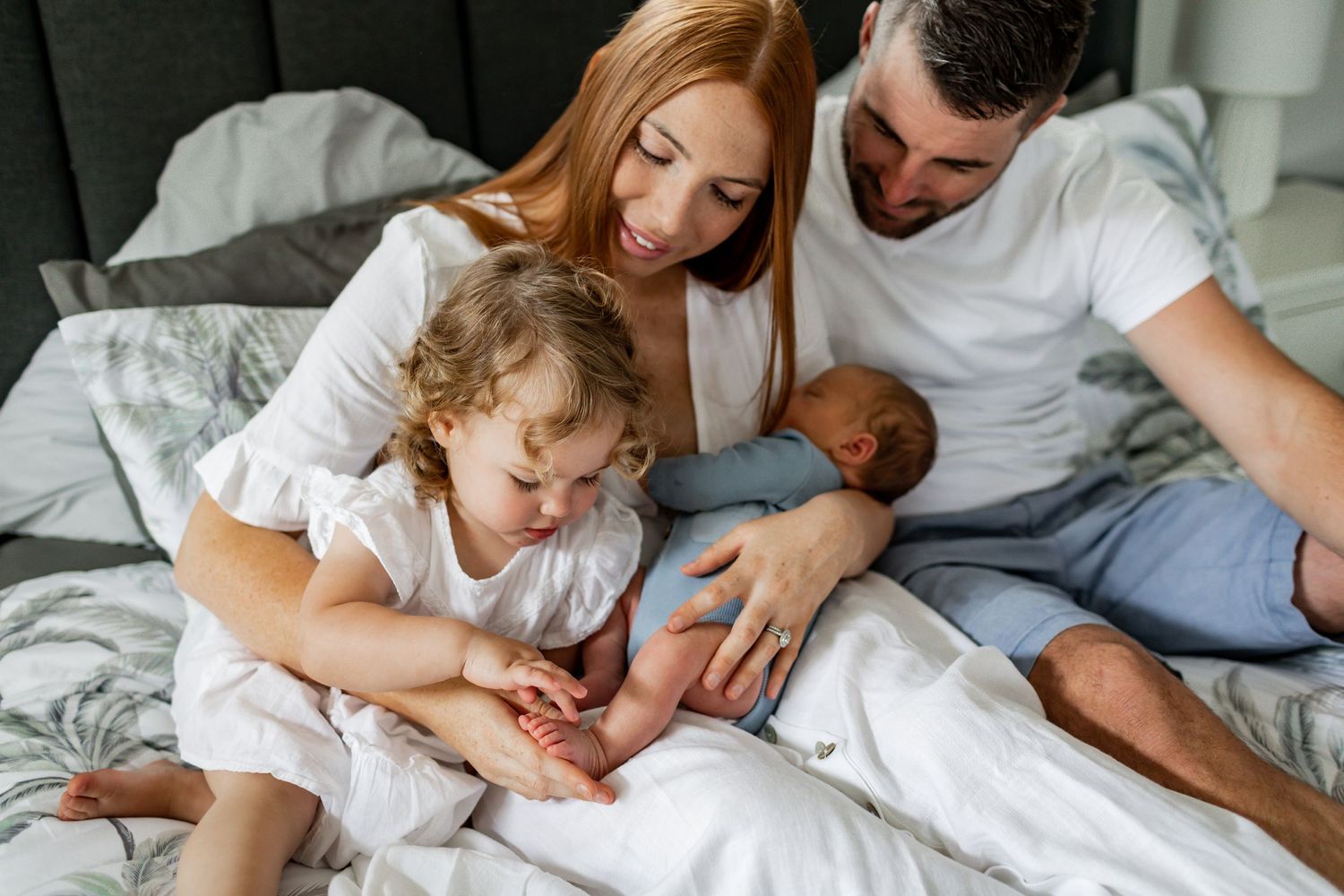 A family lounging together on a gray couch sharing an intimate moment.